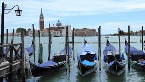 Gondolas amarradas en un muelle con un edificio histórico al fondo.