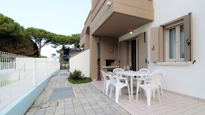Un patio con mesa y sillas, una parrilla y una cerca blanca.