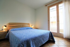A bedroom with a bed, nightstands, and a sliding glass door to a balcony.