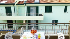 A balcony with a table set for two, featuring a fruit bowl, glasses, and a soccer ball. - Belvilla by OYO Appartamento ROSSO (Jesolo)