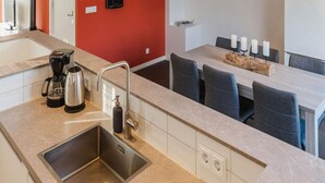 Une cuisine moderne dotée d’un évier en acier inoxydable, d’une machine à café et d’un coin repas avec une table et des chaises.