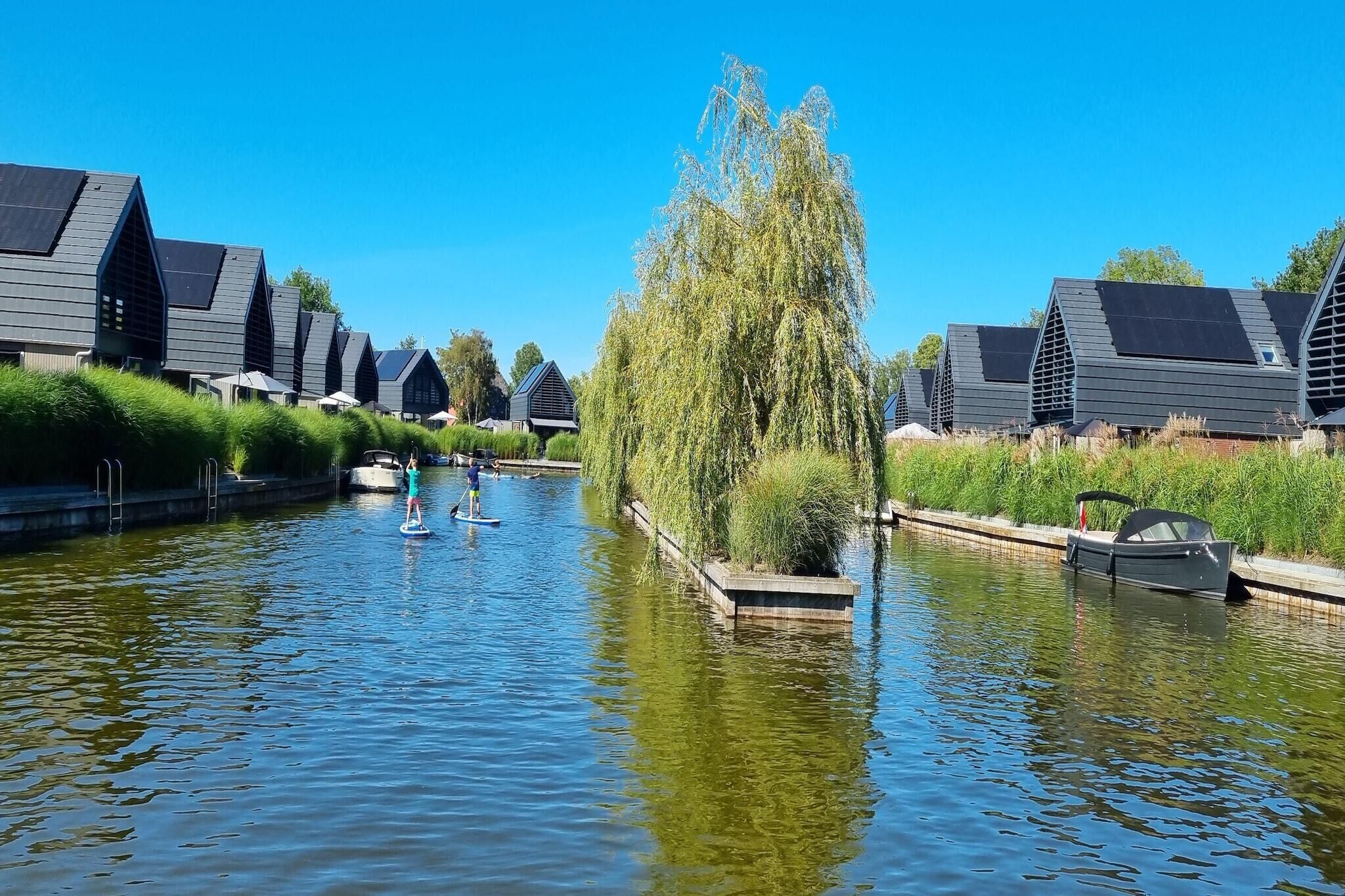 A canal with paddle boats, surrounded by modern buildings with sloped roofs and solar panels.