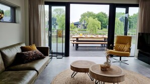 A modern living room with a sofa, a yellow armchair, and a coffee table. - Water Villa in Balk by Slotermeer Lake (Balk)