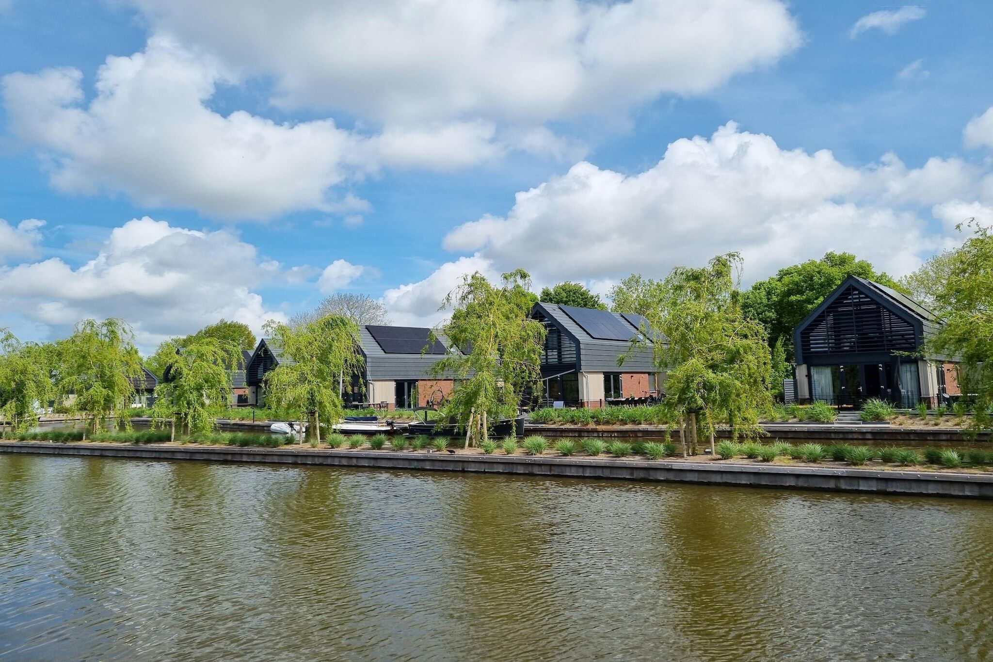 A modern building with a flat roof and large windows, situated next to a calm body of water.