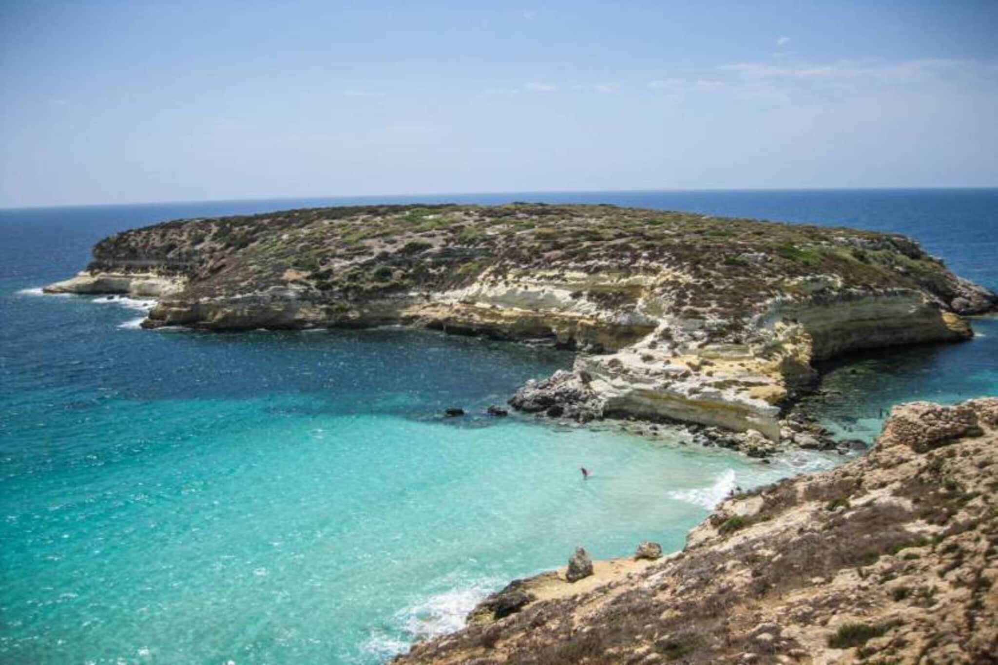 A rocky coastal landscape with clear turquoise waters and a small island.