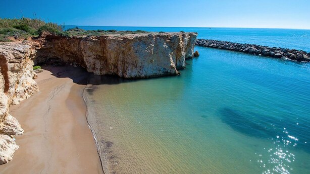 A coastal landscape with a sandy beach, rocky cliffs, and calm blue waters. - Stylish Apartment by the Sea (Ispica)