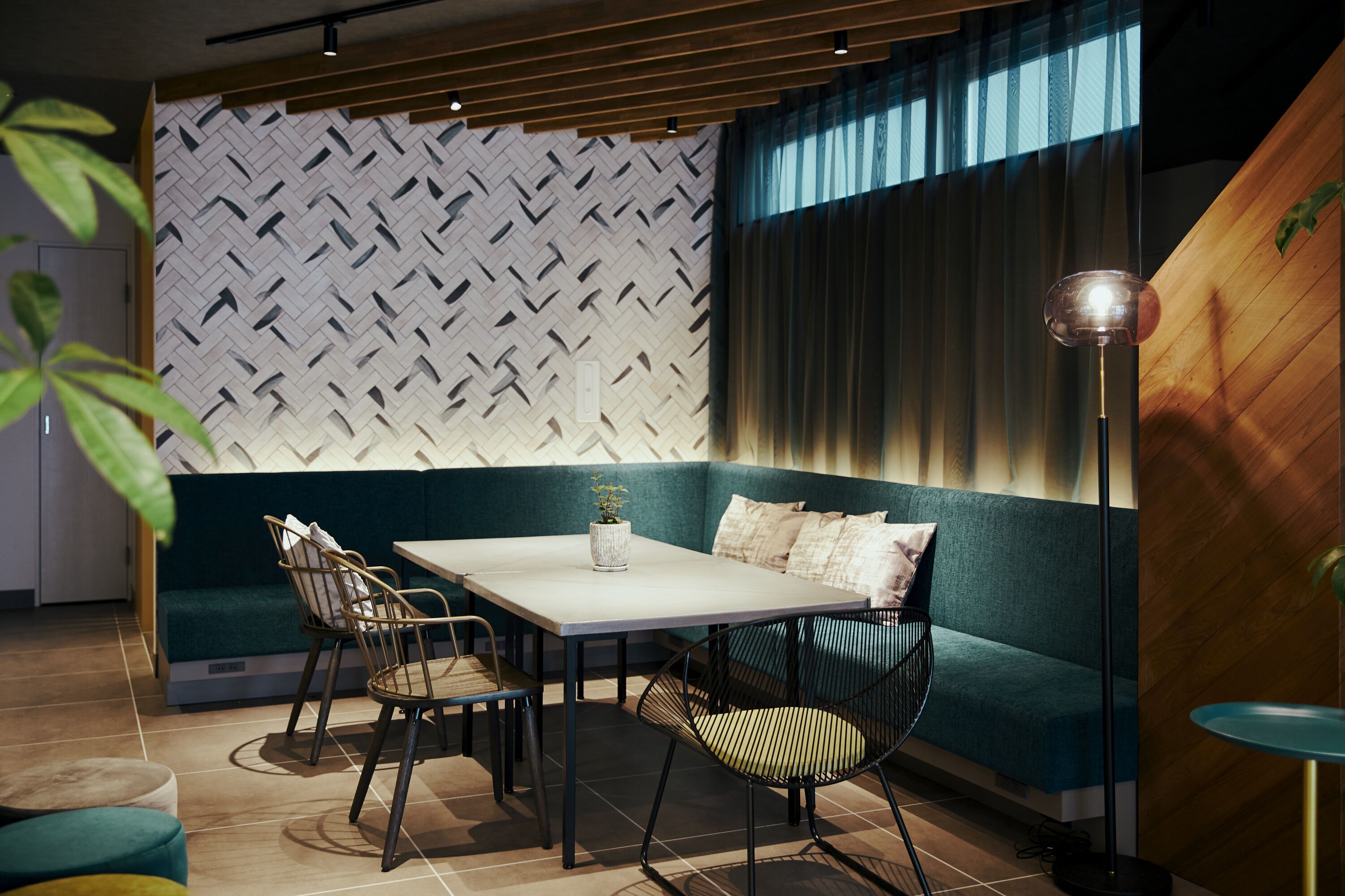 Un espace repas moderne avec un mur orné d’un motif en chevrons, un canapé de couleur turquoise et une table avec des chaises.