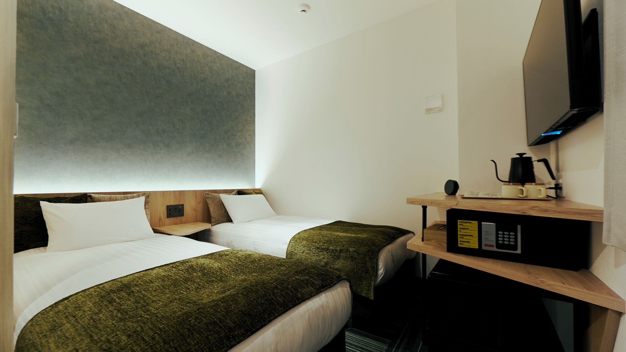 A hotel room with two beds, a TV, a coffee machine, and a small desk.