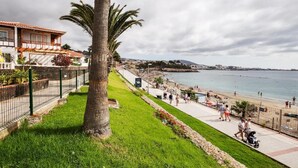 En strandpromenad med en palmpalm, en strand och en byggnad med en balkong.
