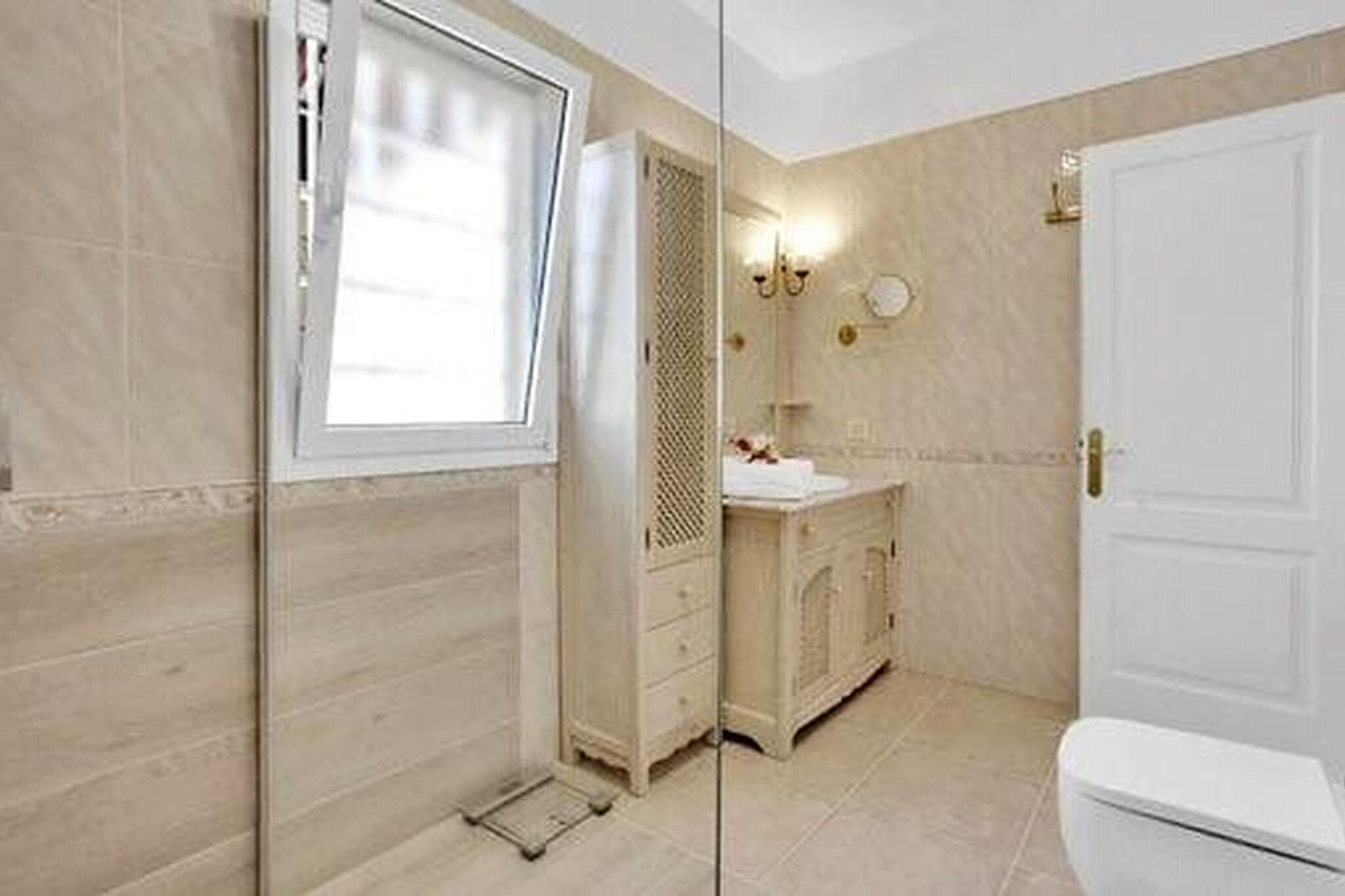 Un bagno con il water, un lavandino, uno specchio e uno spazio doccia.