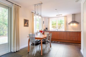 Enjoy meals in the kitchen and dining area with a large window, wooden table, and pendant light.