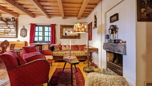 A cozy living room with wooden beams, a sofa, a table, and a fireplace. - Holiday Home in Edlitz near Ski Slopes (Edlitz)