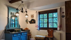 A room with a blue dresser, a wooden chair, a window with curtains, and a hanging light fixture. - Holiday Home in Edlitz near Ski Slopes (Edlitz)