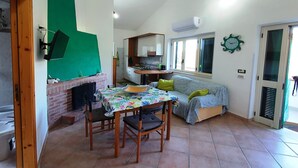 Un espacio habitable compacto con comedor, sofá, chimenea y cocina.