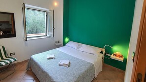 Una habitación con una cama, una silla, un ventanal y una pared verde.