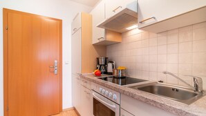 A modern kitchen with a wooden door, stainless steel sink, and a built-in oven. - Apartment in Neustift near Ski Lift (Neustift im Stubaital)