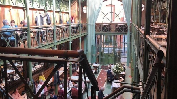 Een meerlaagse bibliotheek met boekenplanken en tafels, met een centrale trap en een glazen plafond.