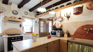 Een keuken met houten kastjes, een fornuis, een magnetron en diverse keukengerei.