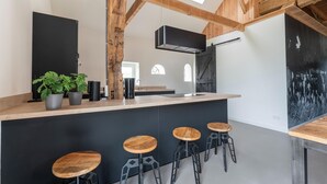 Una cocina moderna con una isla central, vigas de madera y un ventanal grande.