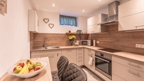 A modern kitchen with a built-in oven, microwave, and a wooden countertop. - Geraeumige Wohnung für 5 Personen in Drachselsried (Drachselsried)