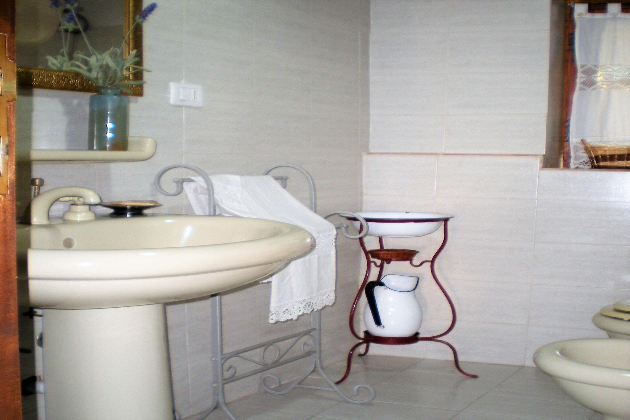 A bathroom with a sink, toilet, and a small table with a pitcher.