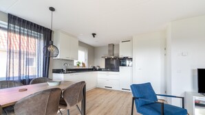 Een moderne keuken met witte kastjes, een zwart aanrecht en een eethoek met een houten tafel en stoelen.