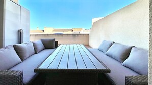 Un patio en la azotea con una mesa de madera larga y dos sofás con cojines.