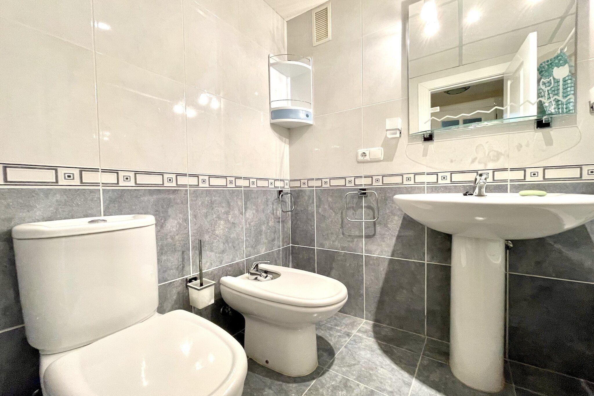 A modern bathroom with a toilet, bidet, and sink.