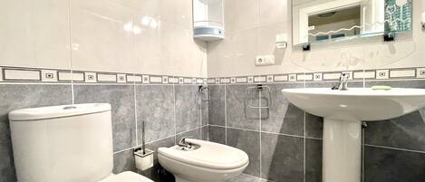 A modern bathroom with a toilet, bidet, and sink.