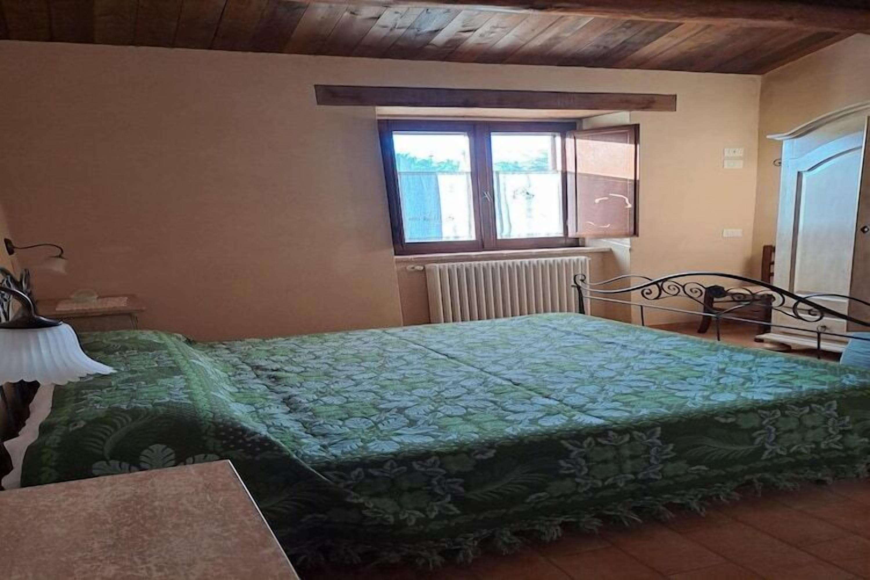 Une chambre à coucher avec un lit, une fenêtre, un radiateur et une porte.