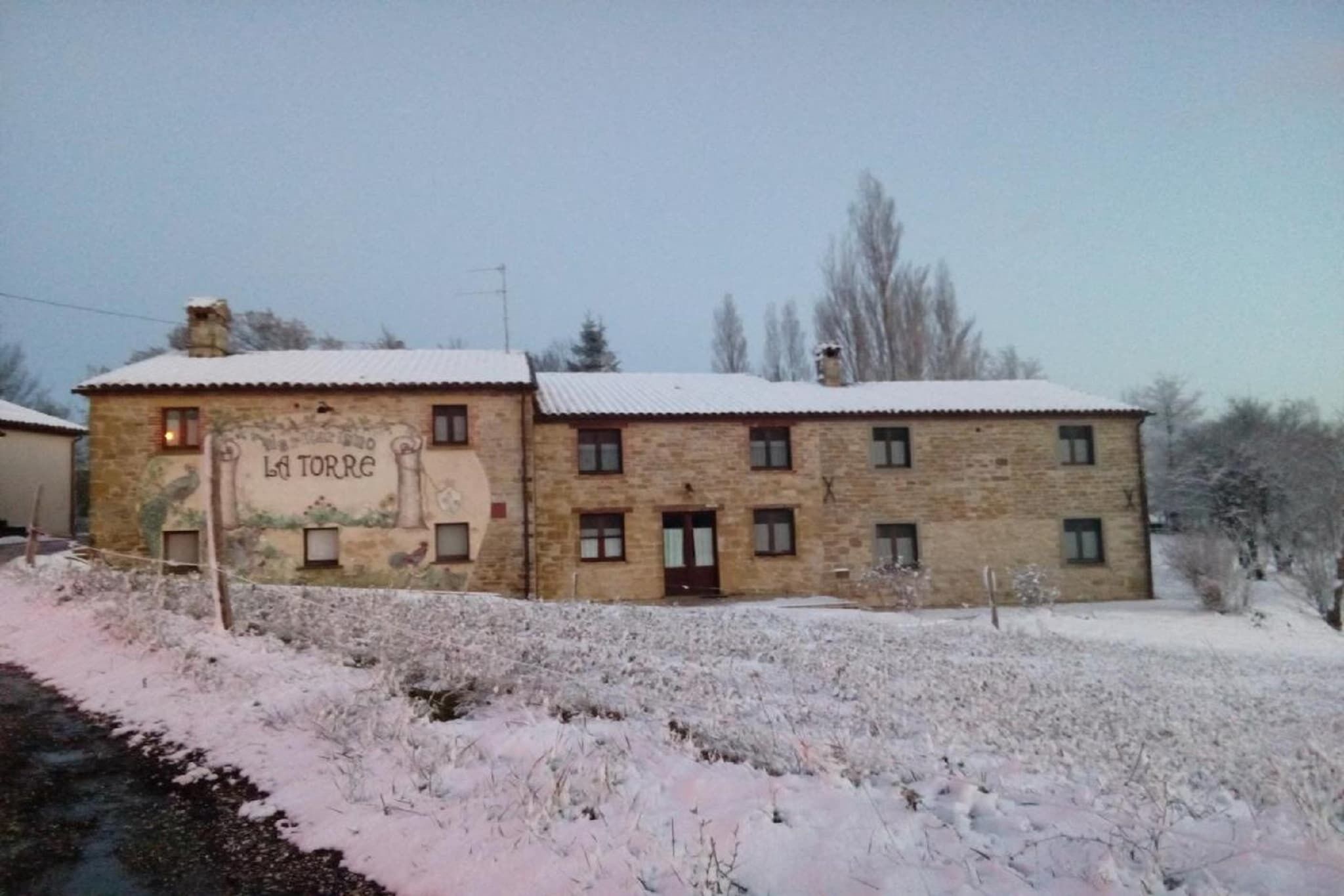 A stone building with a sign reading "La Torre" and a snow-covered landscape.