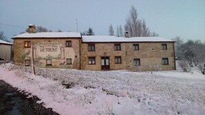 Ein Steinhaus mit einem Schild, auf dem 'La Torre' steht, und einer verschneiten Landschaft.