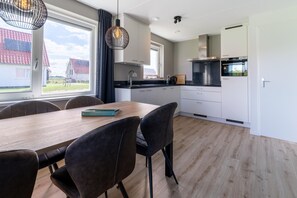 Enjoy a clean and contemporary kitchen with sleek cabinetry, a black countertop, and a dining area with a wooden table and comfortable chairs.