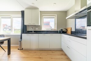 Enjoy a clean and contemporary kitchen with sleek cabinetry and a black countertop, offering a view of the surrounding neighborhood.