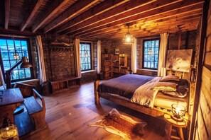 Interior rústico con cama de madera, una mesa de comedor y una pared de piedra.