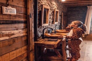 Interior rústico de madera con un letrero que dice 'Salle de Bain', indicando un área de baño.