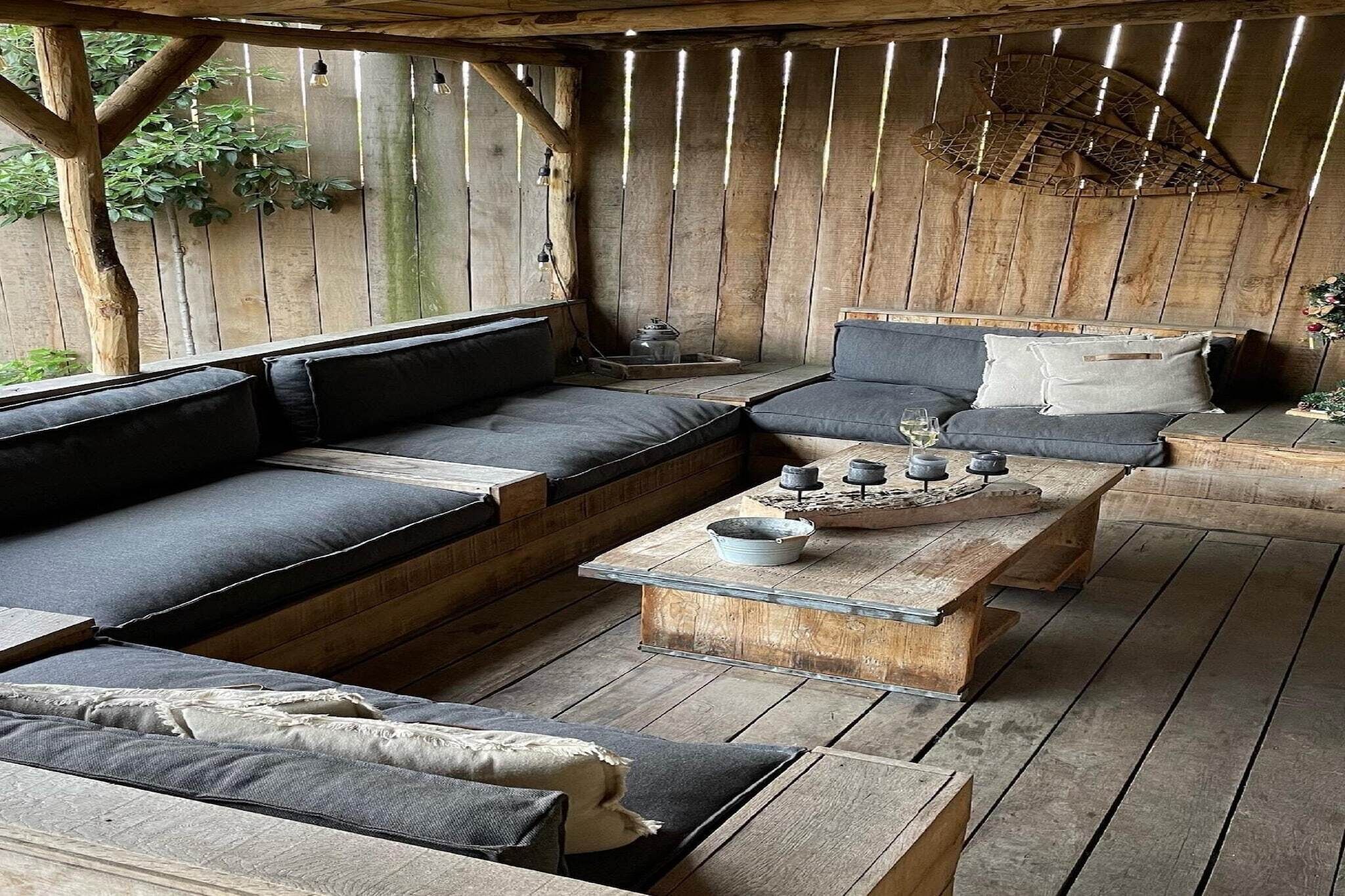 A rustic wooden room with a large sofa, a coffee table, and a small table with decorative items.