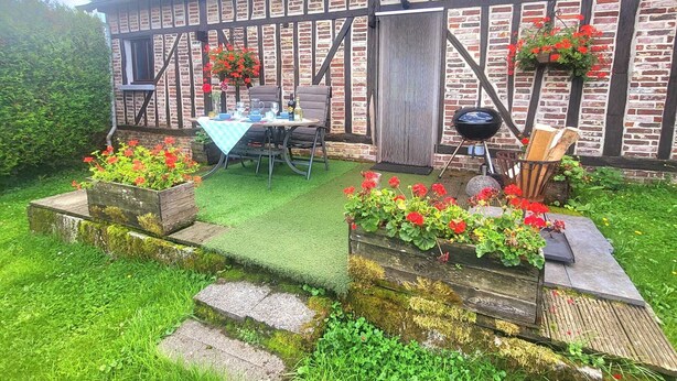 Een traditioneel vakantiehuis met vakwerk, een tuinpatio, terrasmeubels en een barbecuehoek.