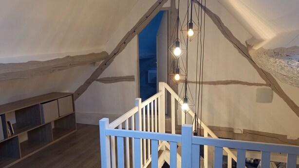 Een houten trap met een witte leuning die leidt naar een vide met een schuine kap.