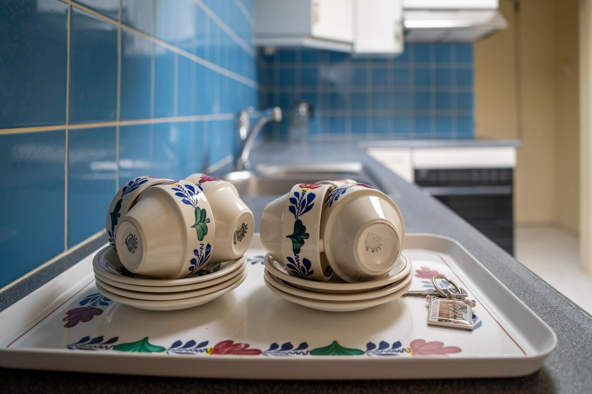 Un plateau avec des assiettes et des tasses empilées, un porte-clés et un plateau décoratif.