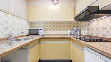 A compact kitchen with a microwave, coffee maker, and stove.