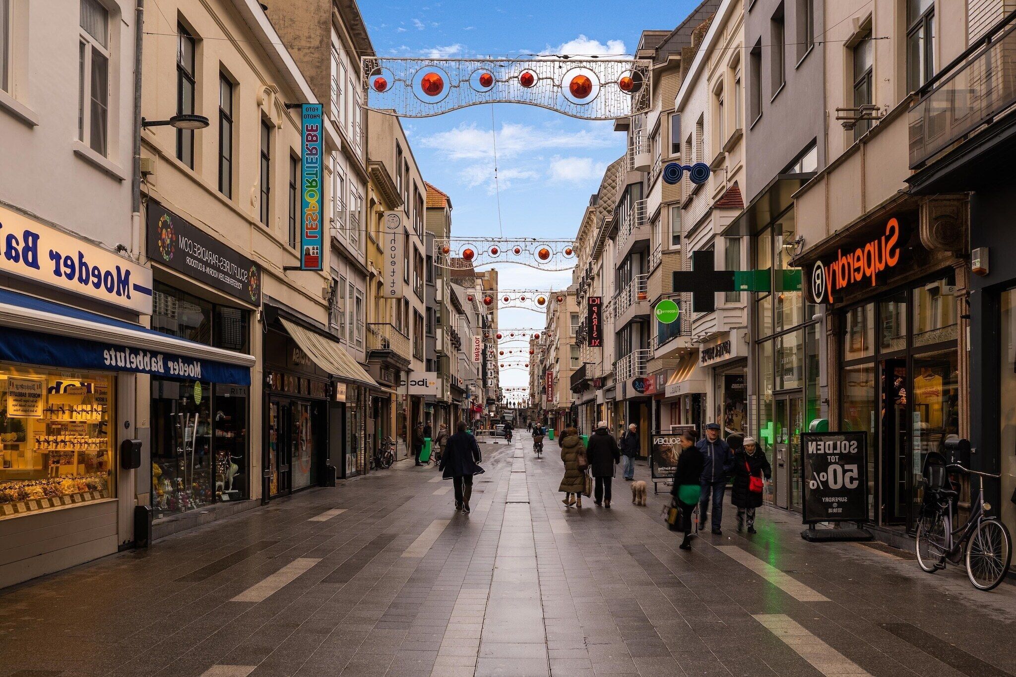 A pedestrian street lined with shops and a sign indicating a 20% discount.