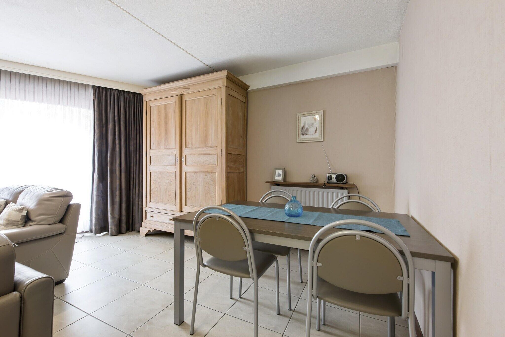 A dining area with a table, chairs, a cabinet, and a radiator.