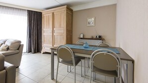 A dining area with a table, chairs, a cabinet, and a radiator. - Pretty apartment on the casino (Blankenberge)