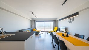 A modern hotel room with a kitchen, dining area, and a large window offering a view of the sea. - Apartment with 3 bedrooms and sea view (Middelkerke)