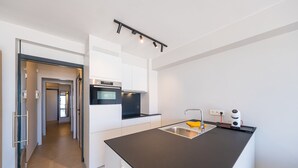 A modern kitchen with a central island, built-in oven, and a sleek countertop. - Apartment with 3 bedrooms and sea view (Middelkerke)
