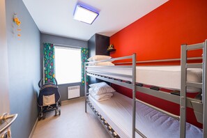 Et soveværelse med køjeseng, vindue, klapvogn og radiator.