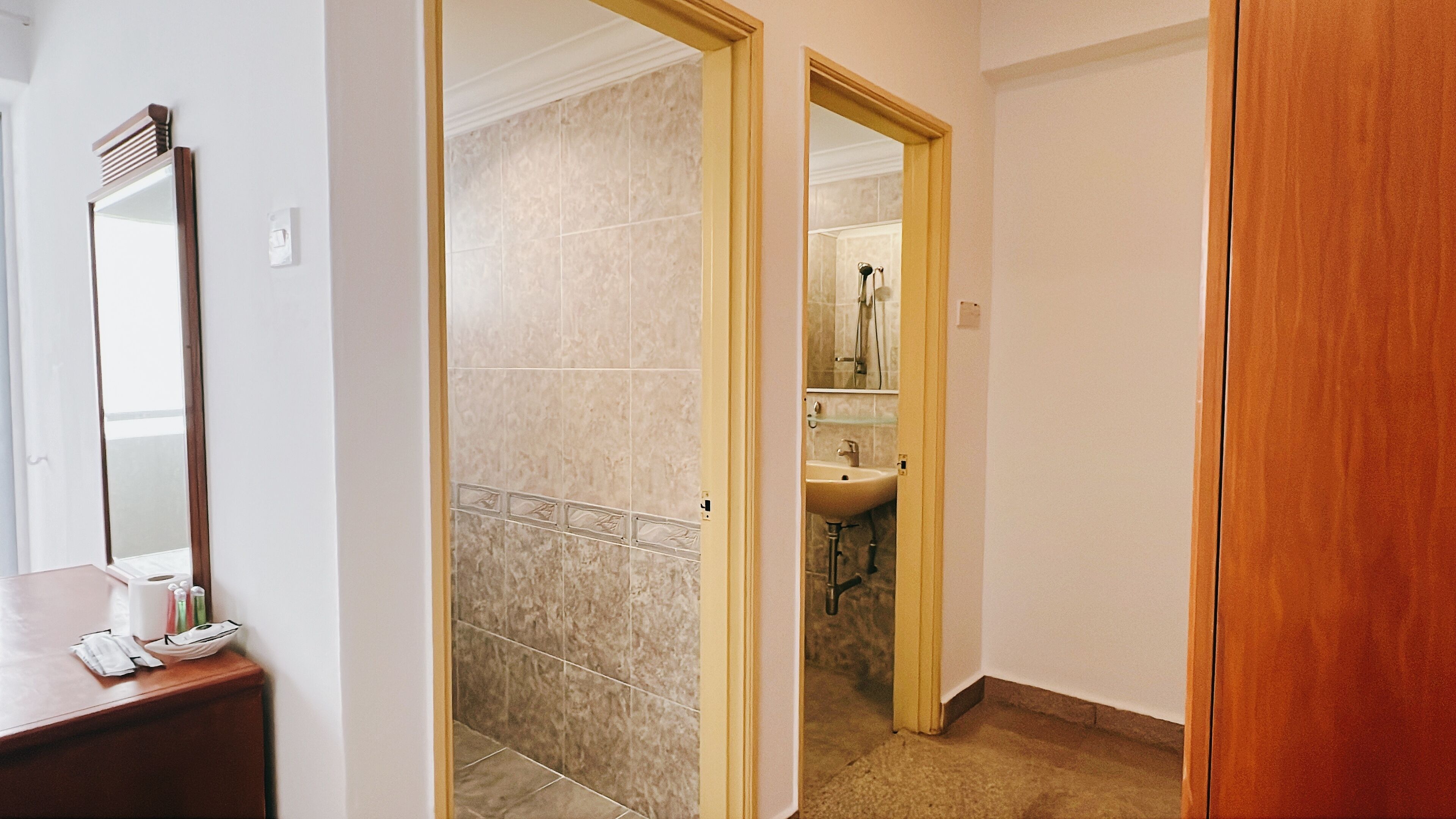 A hallway leading to a bathroom with a sink and mirror.