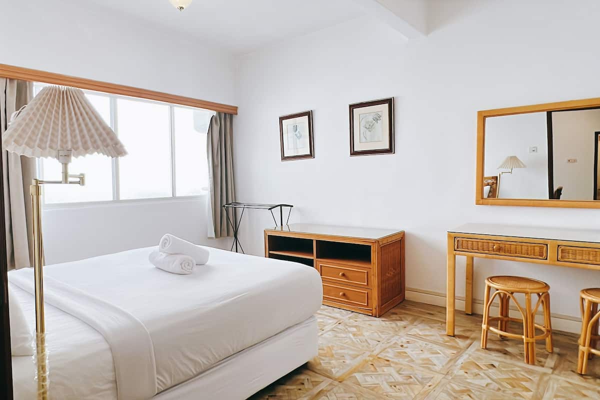 Una habitación de hotel con cama, escritorio, silla, espejo y ventana.