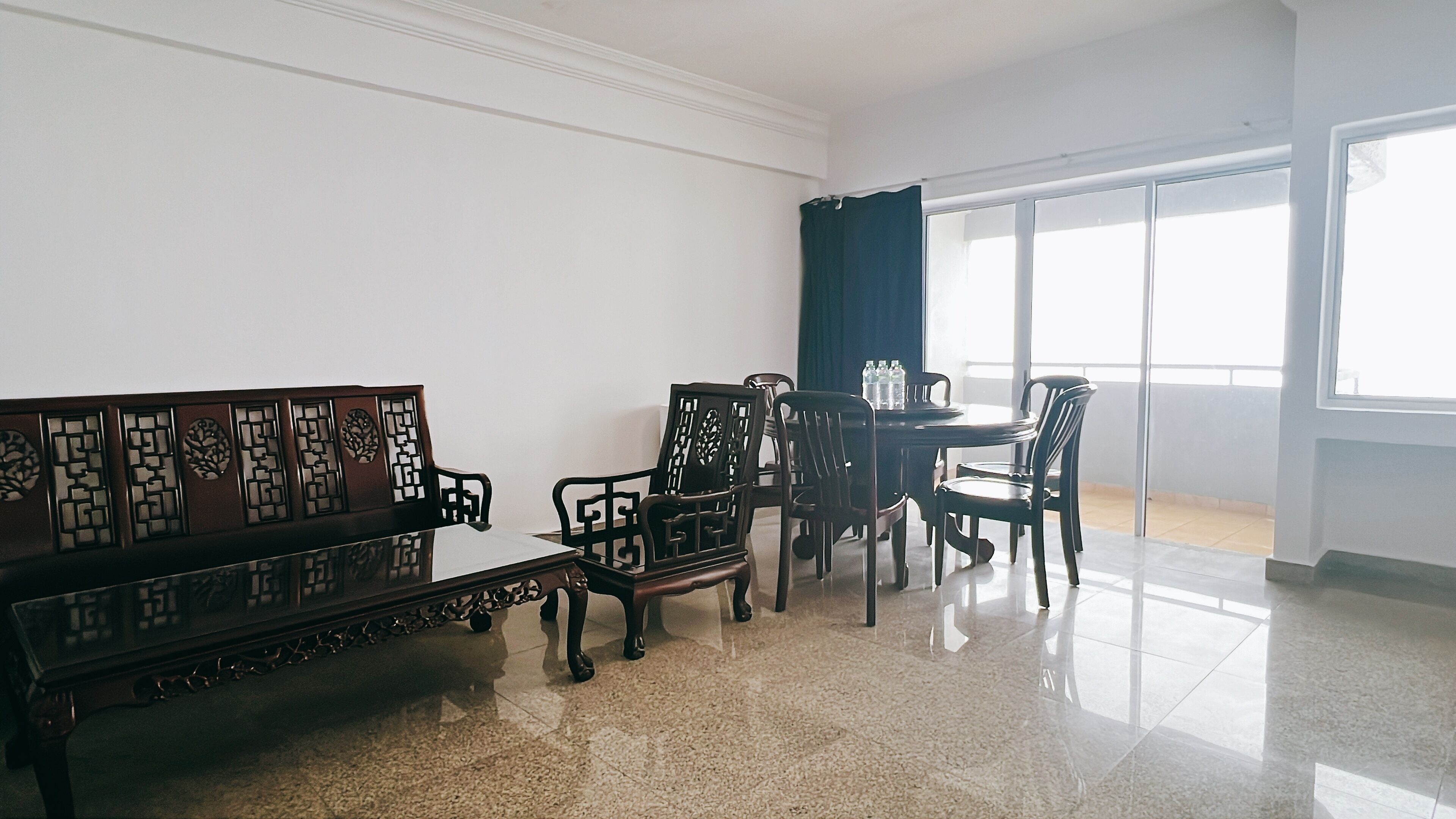 A room with a wooden bench, a dining table with chairs, and a large window with curtains.